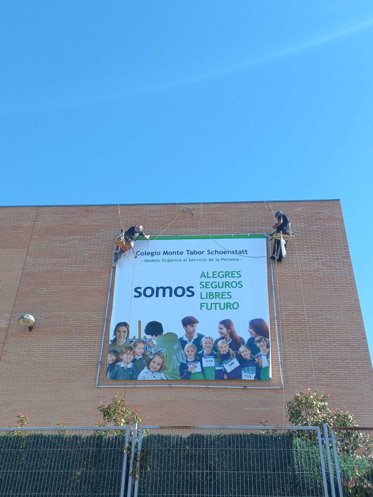 Personal técnico colocando una lona publicitaria exterior realizado por la Agencia de publicidad Camaleón Experience.