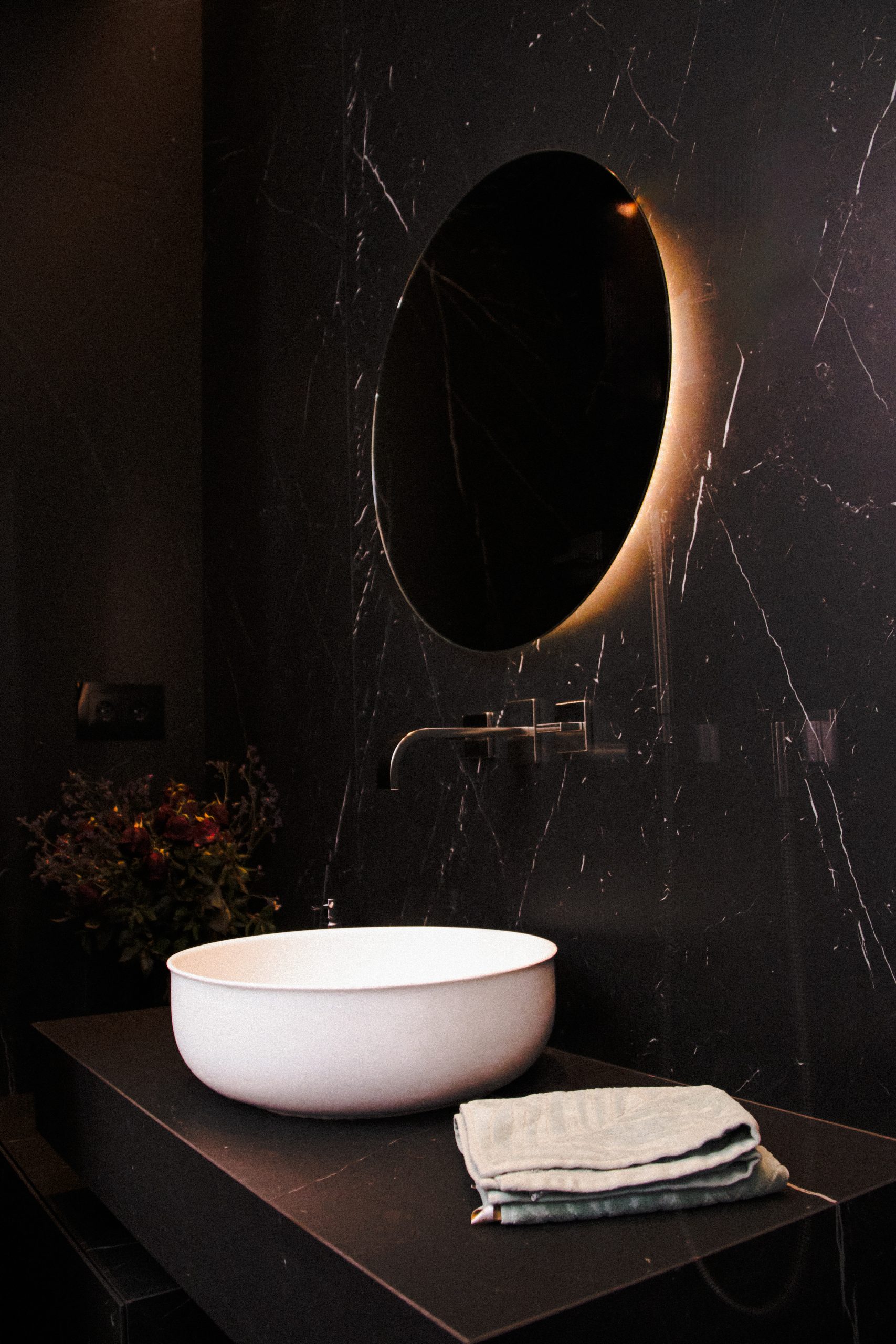 Fotografía profesional de un baño moderno en tonos oscuros.